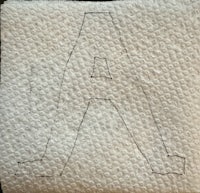 the letter a is embroidered on a piece of cloth